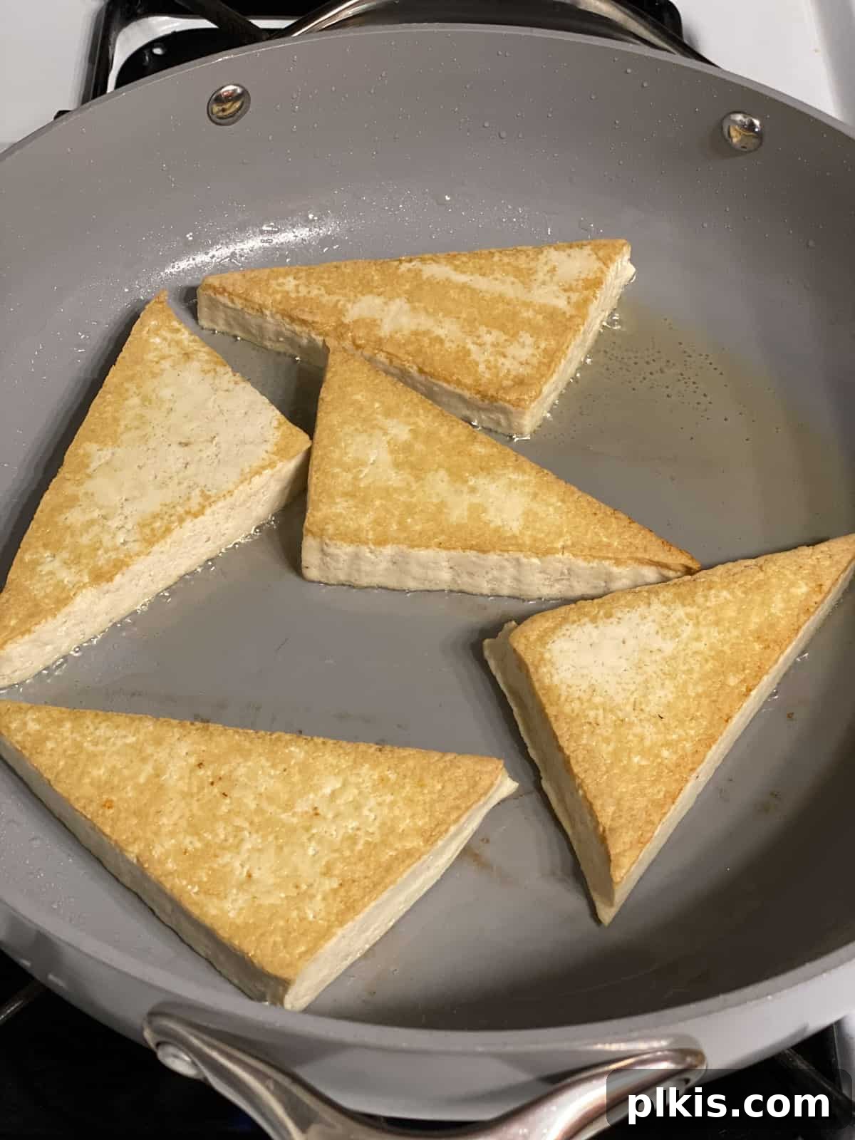 Buffalo Tofu Your Way: Easy Fried, Baked, or Air-Fried 5 Process shot of cooking tofu wedges on a frying pan until golden