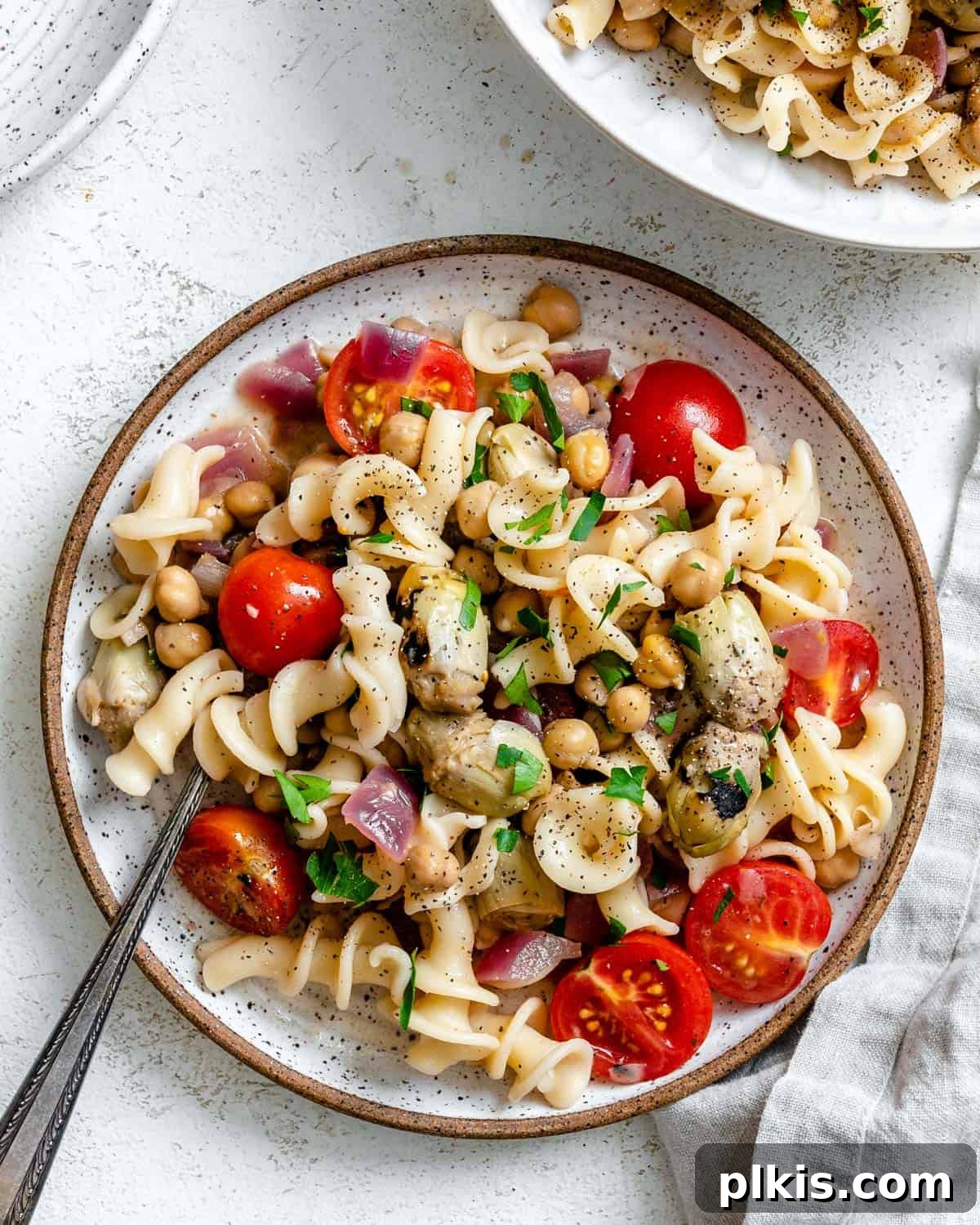 Refreshing Summer Pasta Salad 2 Completed Summer Pasta Salad on a plate, garnished with fresh herbs and cherry tomatoes.