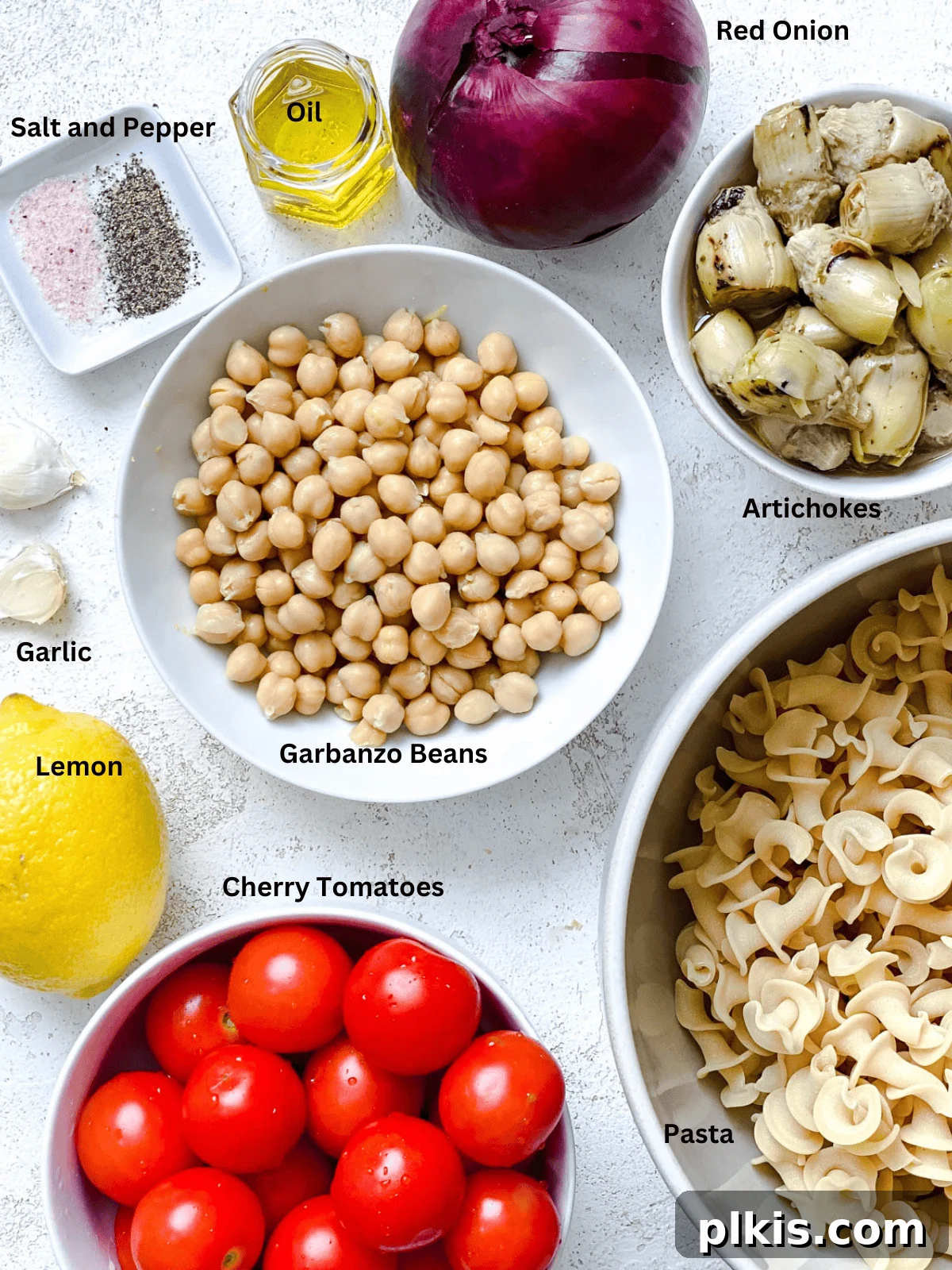 Refreshing Summer Pasta Salad 3 Ingredients for Summer Pasta Salad measured out on a white surface, including pasta, artichokes, chickpeas, and fresh vegetables.