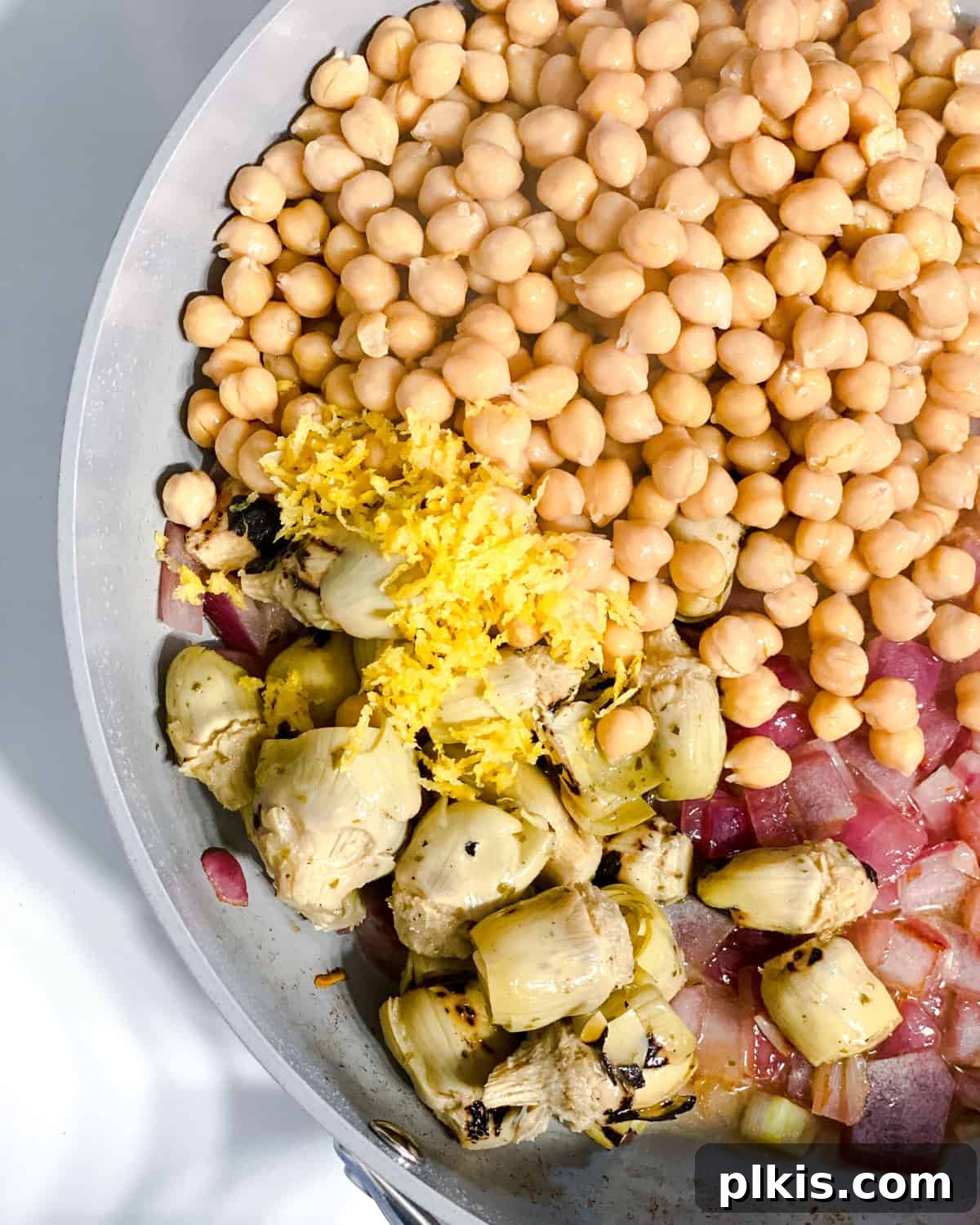 Refreshing Summer Pasta Salad 5 Process shot of vegetables, artichokes, and chickpeas cooking in a pan.