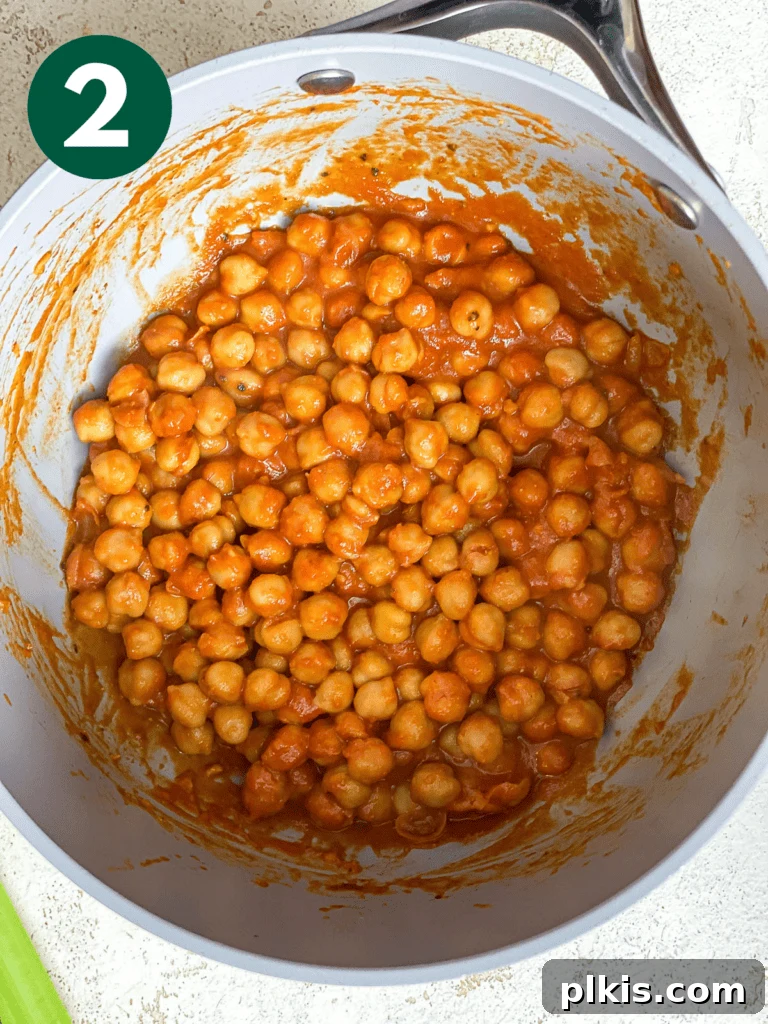 Tangy BBQ Chickpea Wraps 6 Process shot of cooking chickpeas in BBQ sauce in a pot, simmering gently.