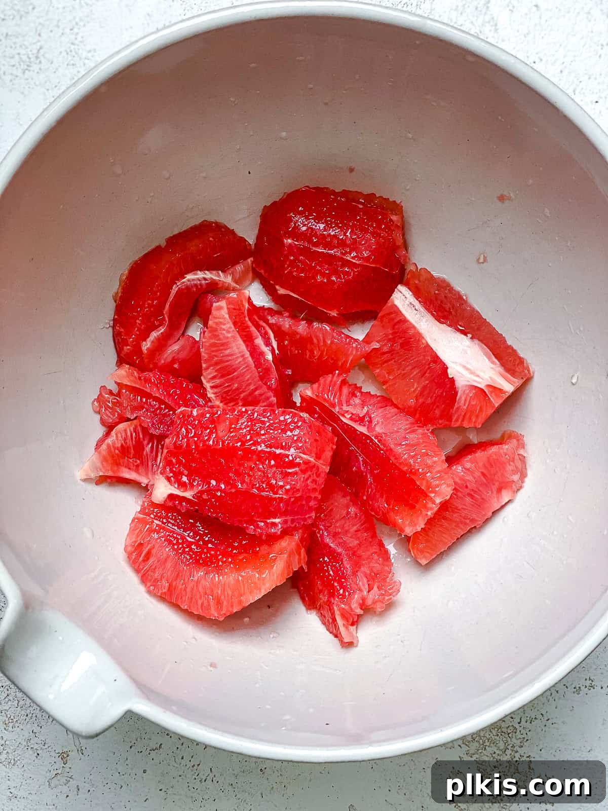 Process shot showing perfectly segmented grapefruit in a bowl, ready to be added to the salad.