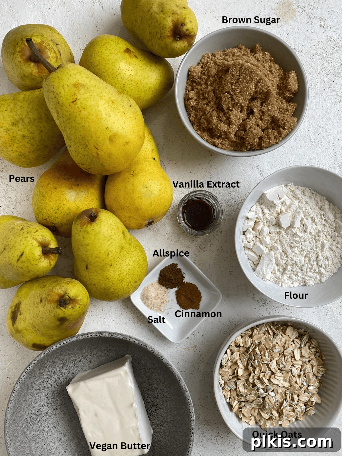 All the necessary ingredients for Easy Pear Crisp [Vegan Pear Crumble] meticulously measured and displayed on a pristine white surface, ready for preparation.