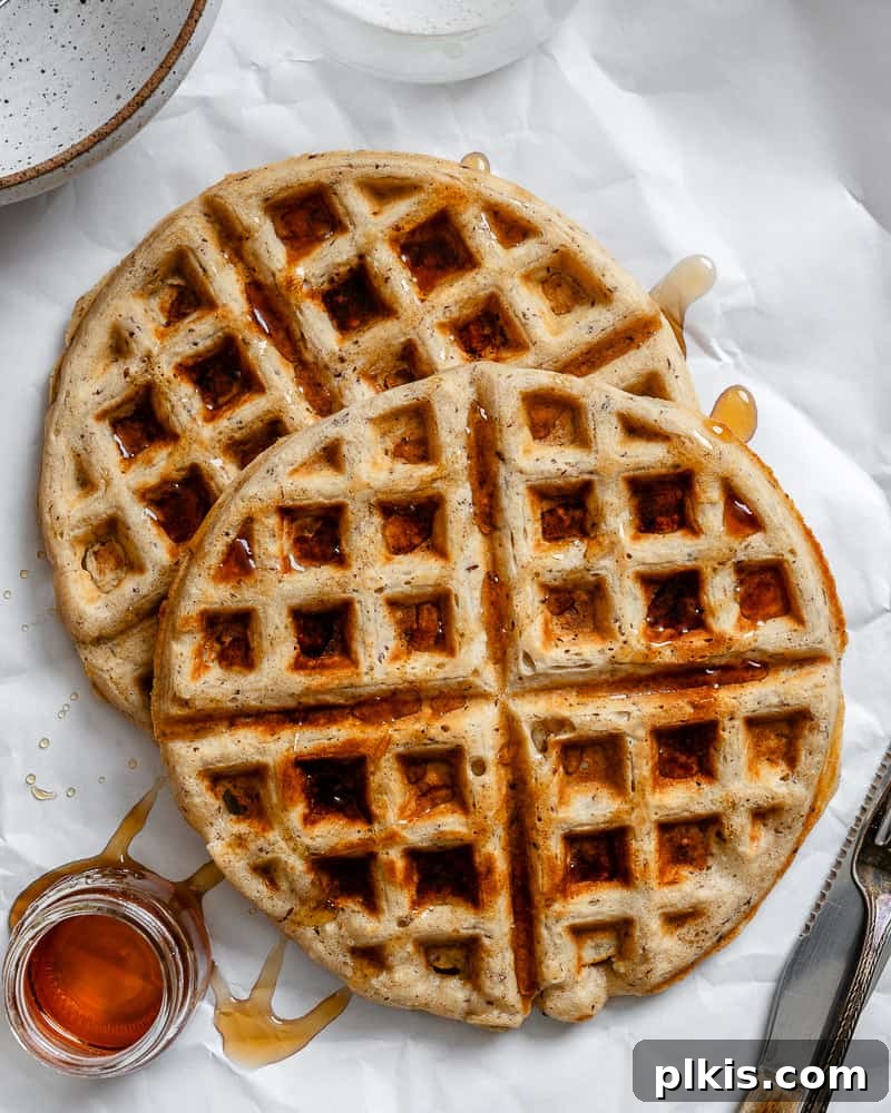 Plant-Based Waffles 2 A beautifully stacked plate of golden-brown vegan waffles, generously drizzled with rich maple syrup, ready to be enjoyed.