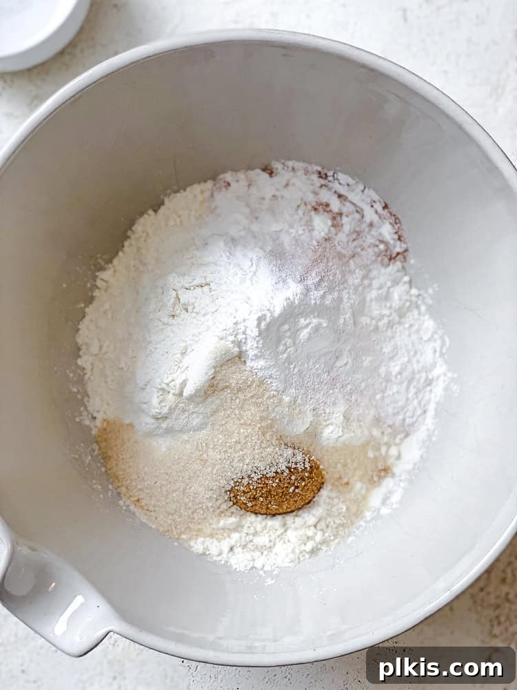 Plant-Based Waffles 6 A large bowl filled with dry ingredients like flour, sugars, baking powder, salt, and cinnamon, showing the formation of a 'well' in the center, preparing for the liquid mixture.