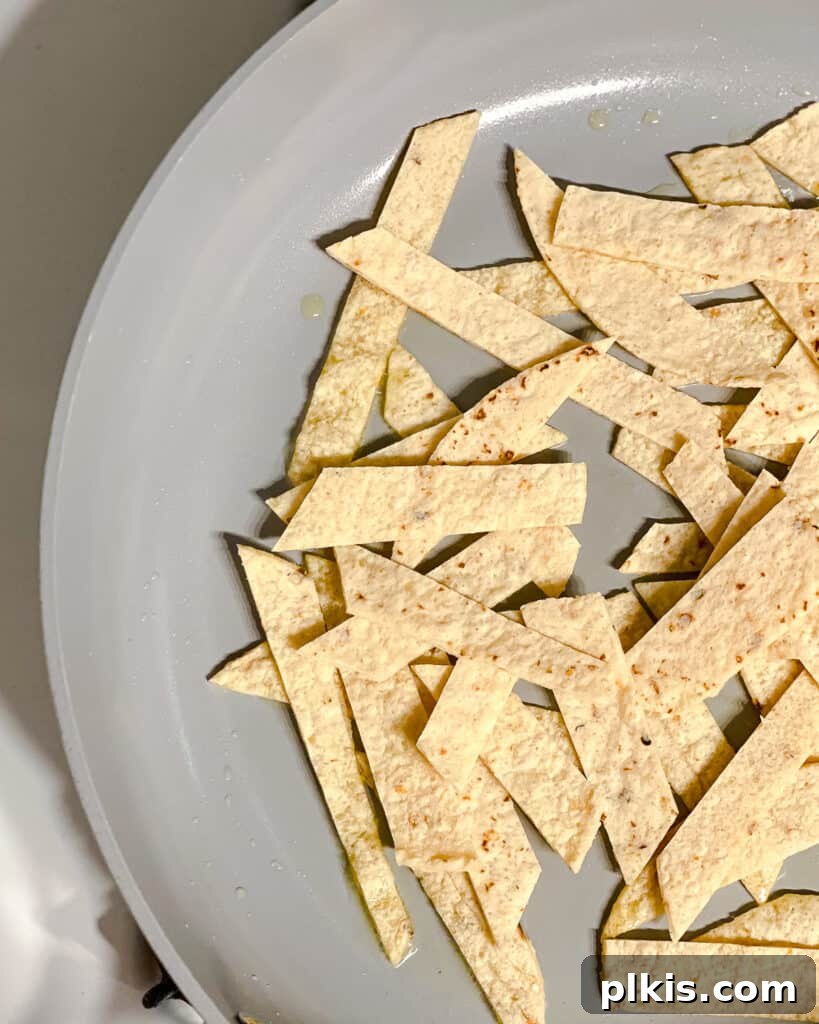 Vegan Chilaquiles Red or Green 5 Process shot showing tortilla strips freshly added to a hot frying pan, beginning to crisp.