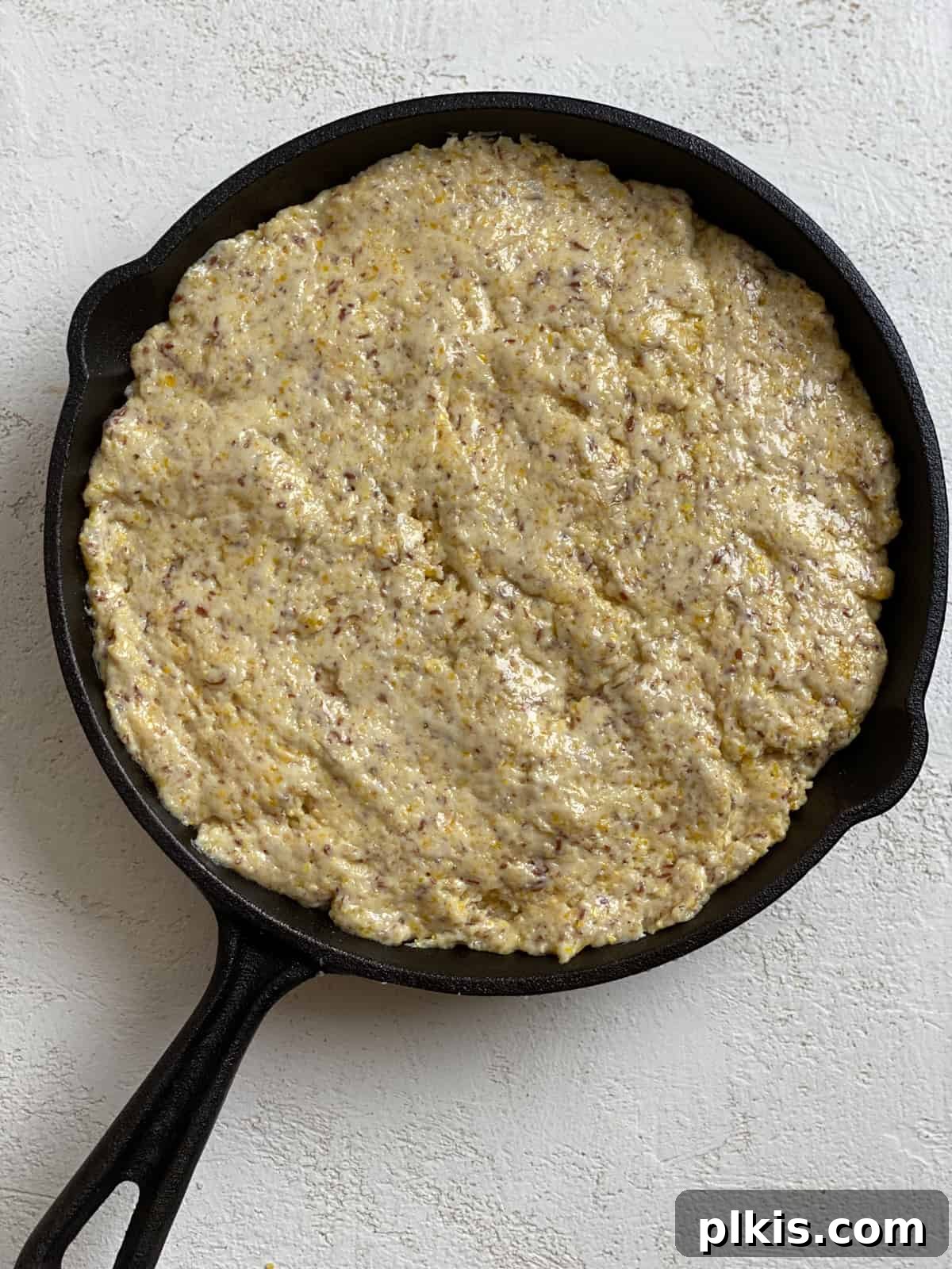 Golden Crust Vegan Cornbread in a Cast Iron Skillet 13 process shot of adding cornbread mixture to cast iron skillet before baking