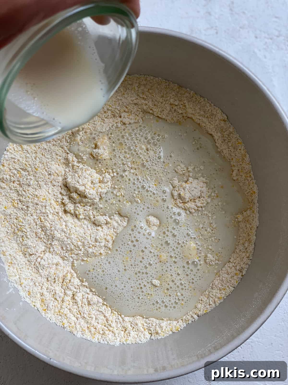 Golden Crust Vegan Cornbread in a Cast Iron Skillet 8 process shot of adding milk to bowl of dry ingredients