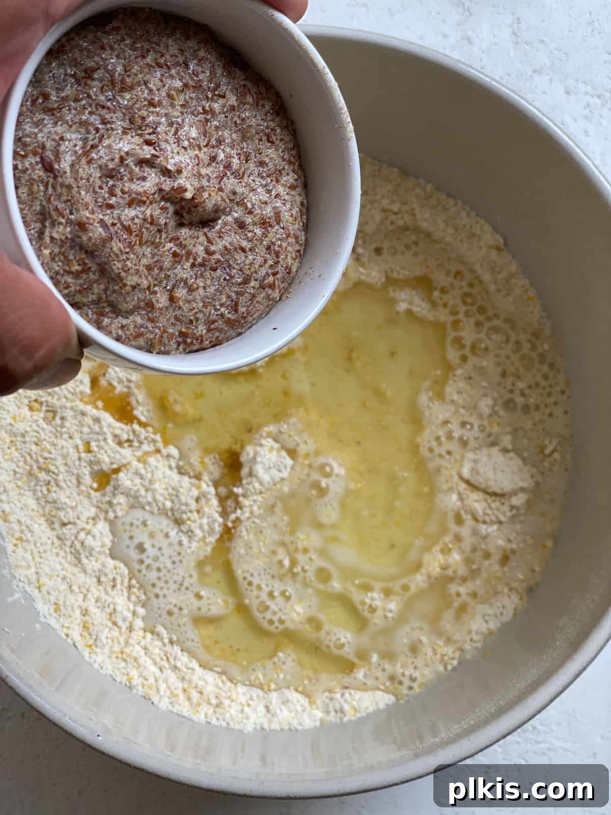 Golden Crust Vegan Cornbread in a Cast Iron Skillet 10 process shot of adding flaxseed mixture to bowl of dry ingredients