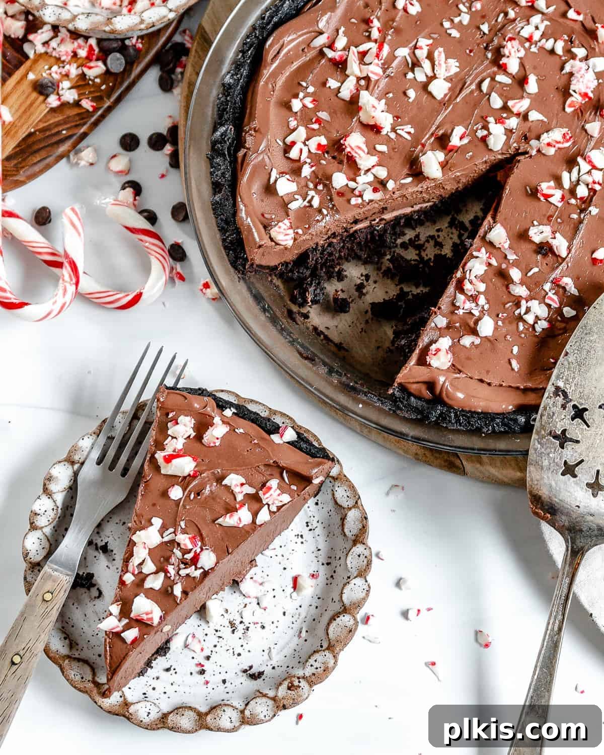 Decadent Vegan Peppermint Chocolate Pie 2 A delectable slice of Silken Chocolate Peppermint Pie, perfectly plated with the rest of the pie blurred in the background, showcasing its rich layers and festive topping.