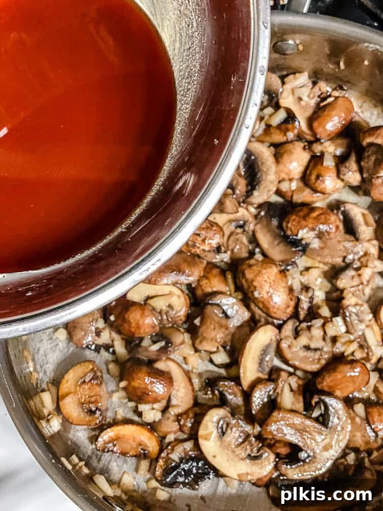 Velvety Polenta with Earthy Mushrooms 6 Process shot showing a mixture of soy sauce, lime juice, water, and tomato paste being added to the pan with mushrooms.