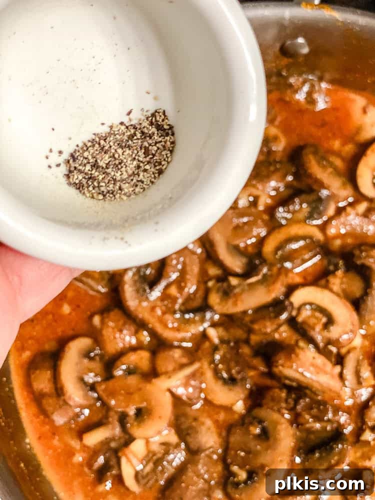 Velvety Polenta with Earthy Mushrooms 7 Process shot showing black pepper being sprinkled into the pan of mushroom ragu.