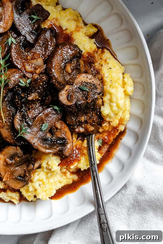 Velvety Polenta with Earthy Mushrooms 8 Completed Creamy Polenta with Mushrooms on a plate, garnished with fresh basil leaves.