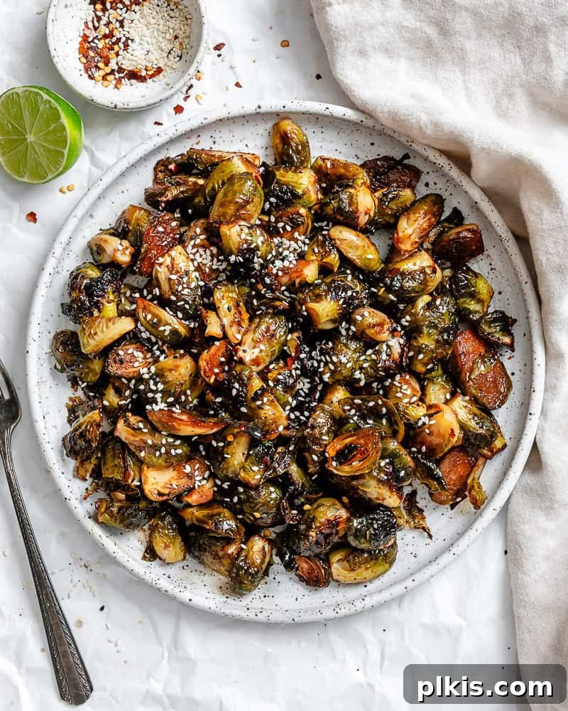 Completed Crispy Brussels Sprouts on a plate, garnished with sesame seeds and chili flakes.