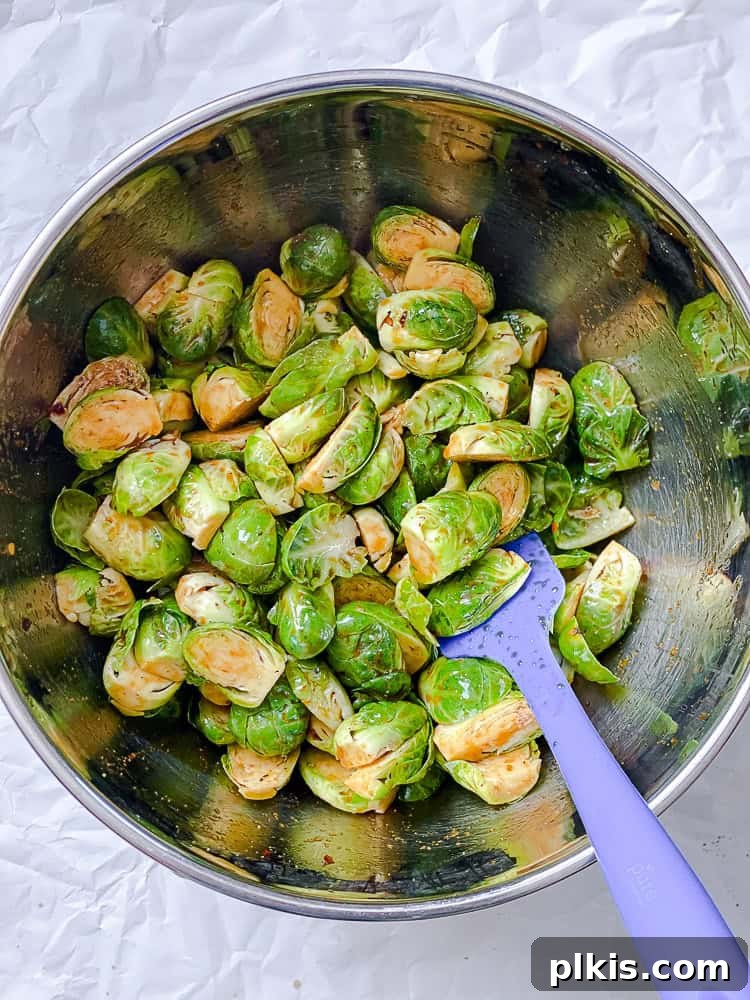 Process shot of mixing Brussels sprouts in bowl with sauce.