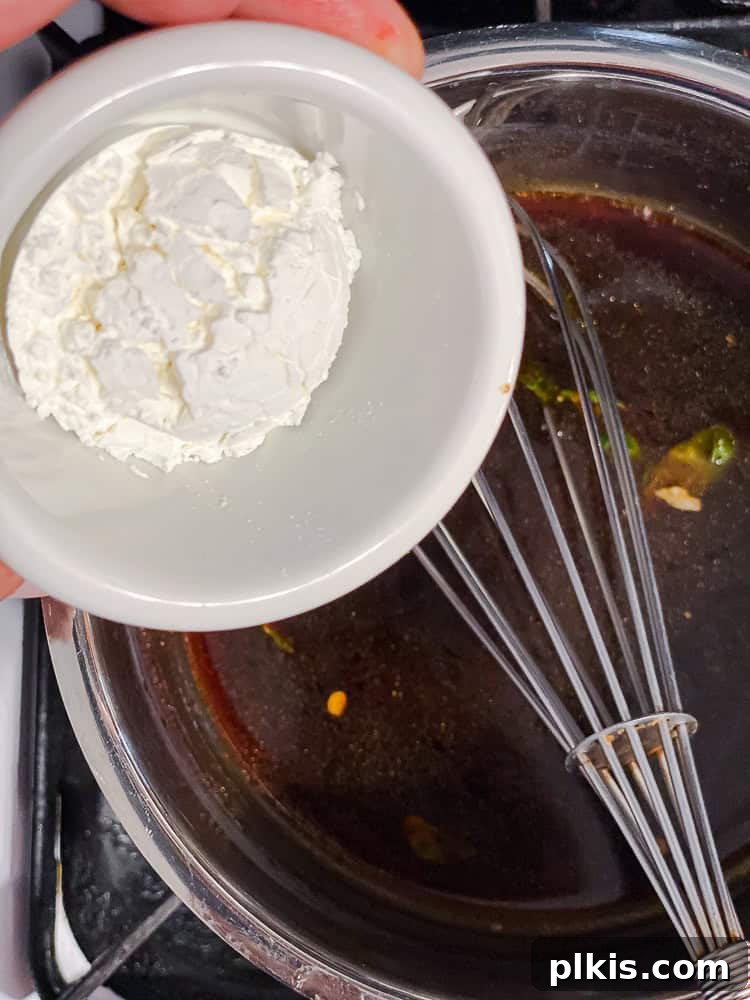 Process shot showing adding cornstarch to the reserved sauce in a saucepan.