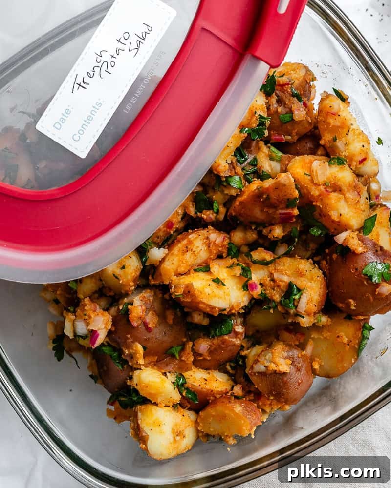 Completed French potato salad perfectly portioned and sealed in a clear storage container, ready for the fridge.
