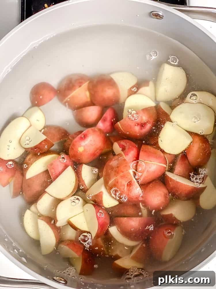 Process shot showing chopped red baby potatoes in a pot of water.