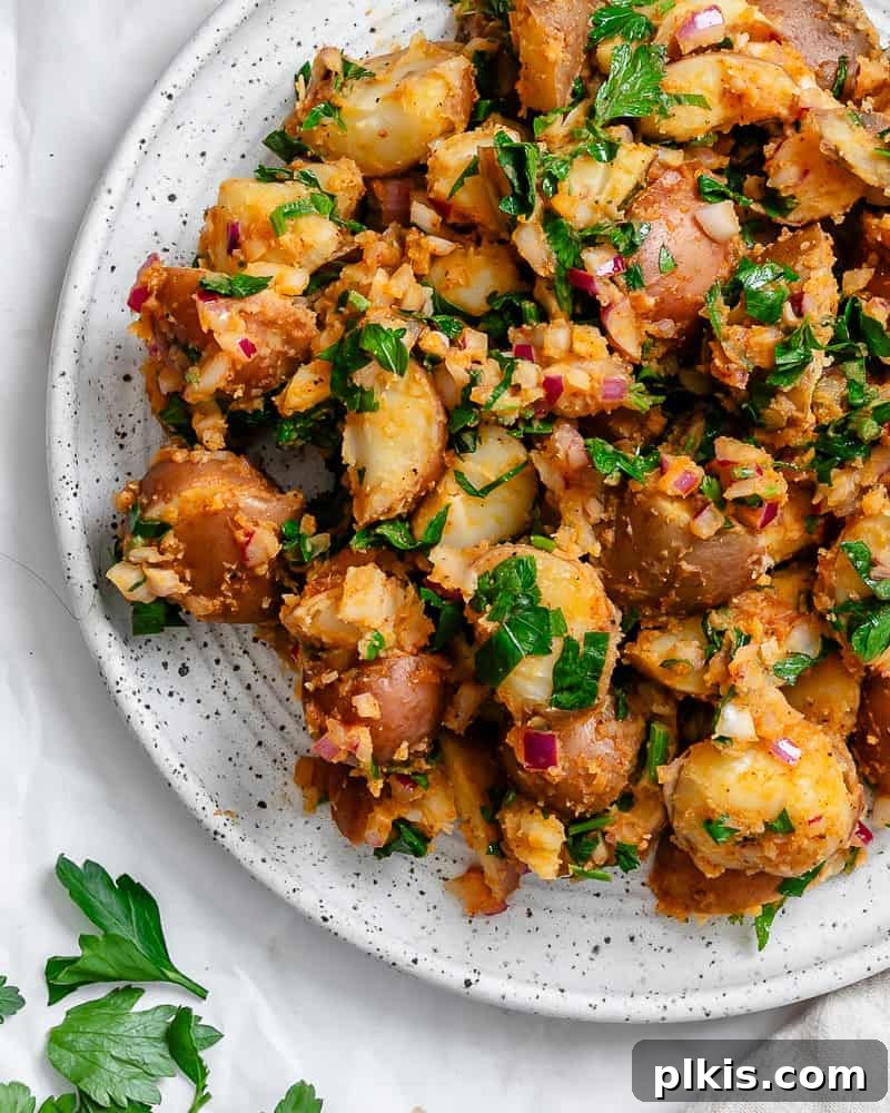 Completed French potato salad, elegantly presented on a white plate, showcasing its fresh and inviting appearance.