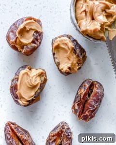 process of carefully spooning peanut butter into a pitted date on a white surface