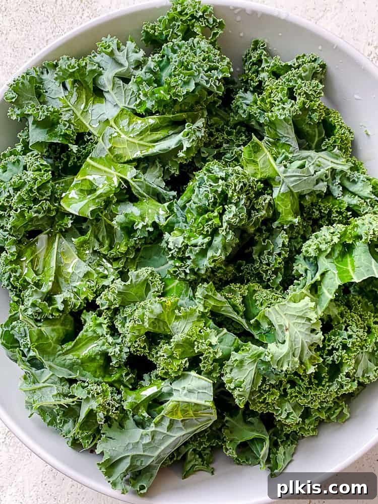 Process shot of mixing oil and kale together by hand.