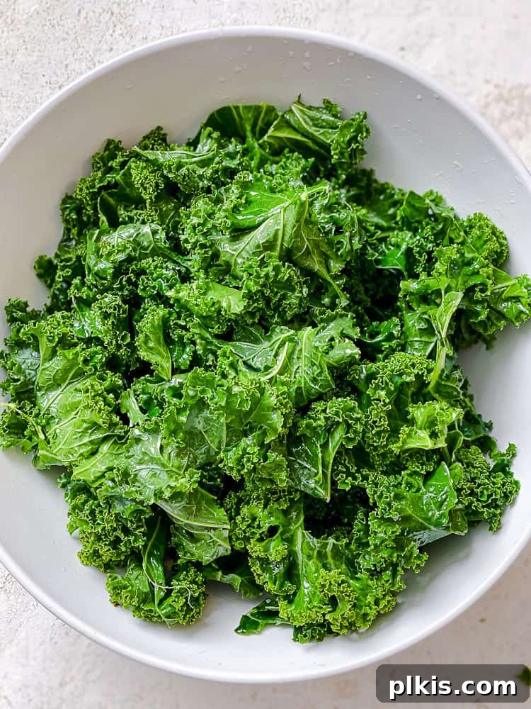 Process shot of kale fully coated in oil, ready for seasoning.