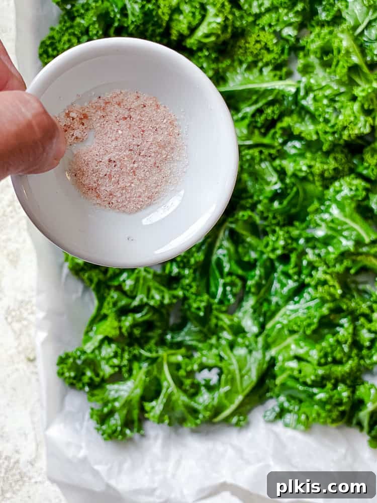 Process shot of adding salt to the oiled kale.