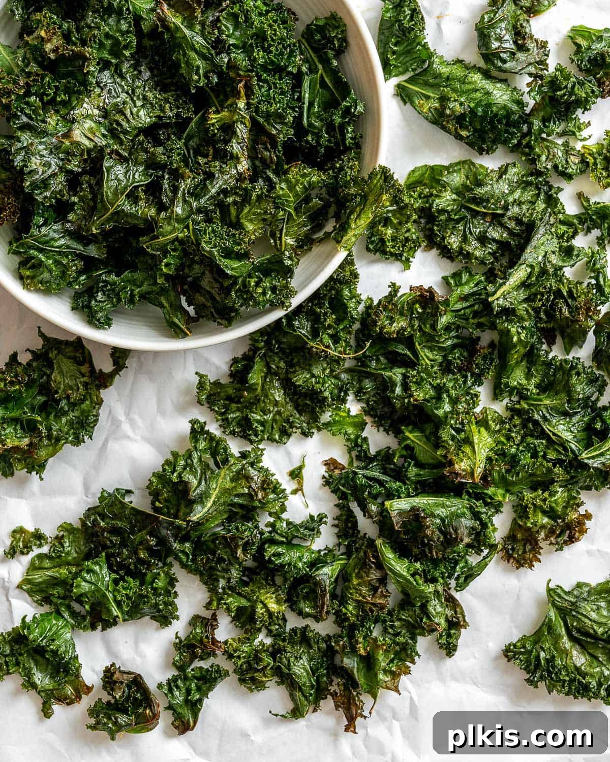 A vibrant bowl of completed Crispy Baked Kale Chips, perfectly seasoned and ready for snacking.