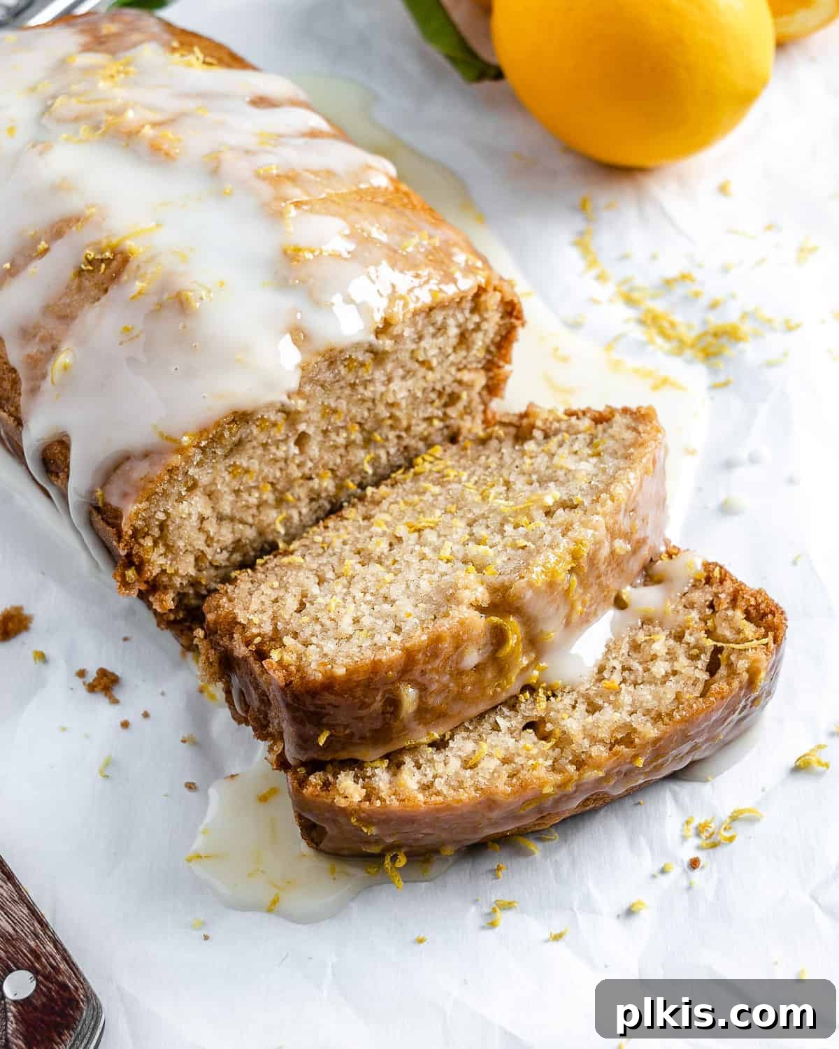 Bright & Tangy Vegan Lemon Loaf 2 A perfectly baked and sliced vegan lemon loaf cake, showing its moist crumb and bright yellow color, against a clean white background. Some slices are stacked, revealing the tender interior.