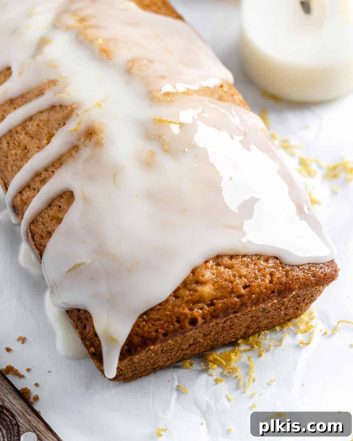Bright & Tangy Vegan Lemon Loaf 8 A whole vegan lemon loaf cake, golden brown and perfectly baked, sitting on a pristine white surface, ready to be sliced and enjoyed.
