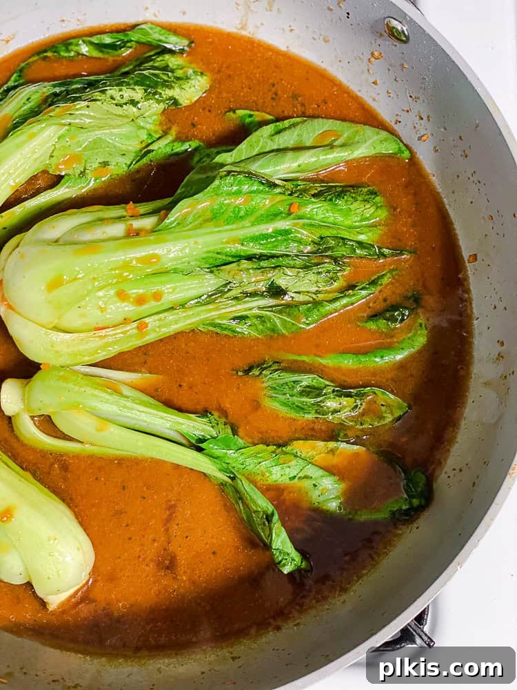 Yaki Udon Stir Fry 7 Process shot showing baby bok choy being added to a hot pan with stir-fry sauce.