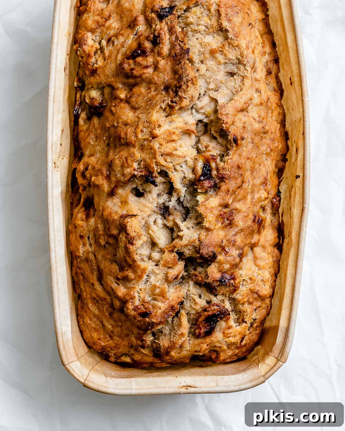 Effortless Vegan Banana Bread Applesauce Enhanced 2 Completed Easy Vegan Banana Bread (With Applesauce) in a loaf pan against a white background, showcasing its golden-brown crust and moist texture.