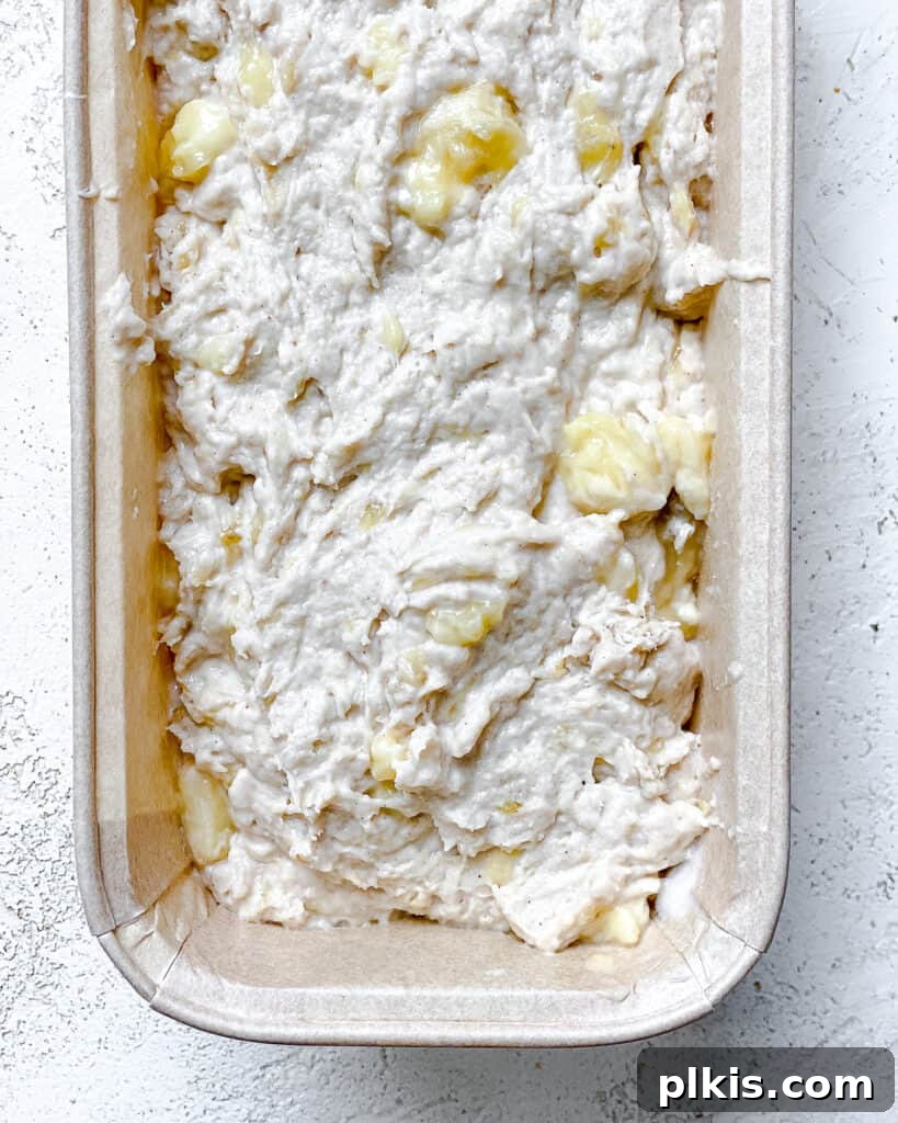 Effortless Vegan Banana Bread Applesauce Enhanced 7 Process shot of adding the prepared banana bread batter to a greased loaf pan, ready for baking.