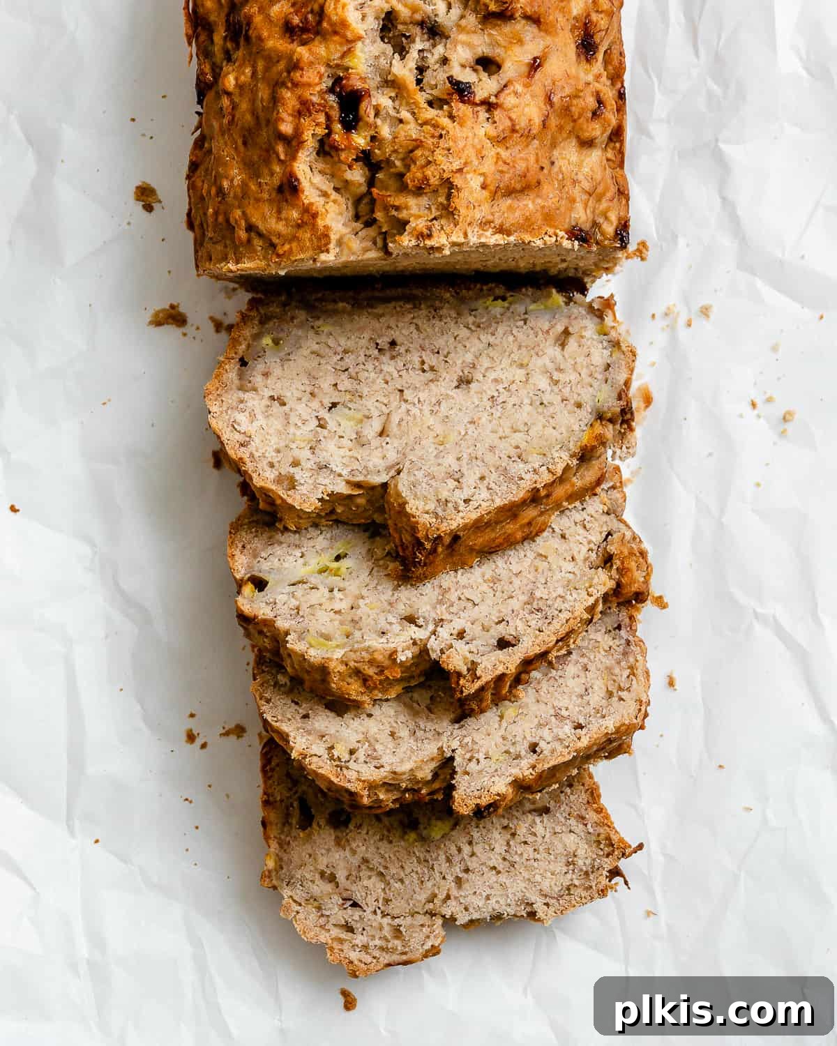 Effortless Vegan Banana Bread Applesauce Enhanced 8 Completed sliced Easy Vegan Banana Bread (With Applesauce) in a loaf pan against a white background, highlighting its moist interior and perfect slices.