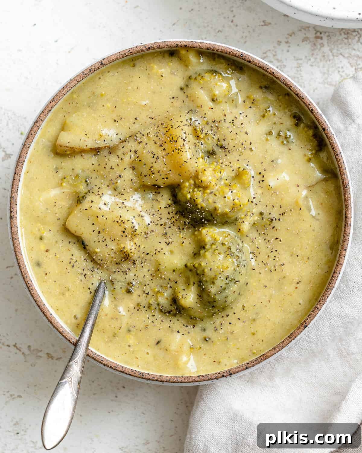 A steaming bowl of completed Vegan Broccoli Potato Soup, garnished with fresh herbs.