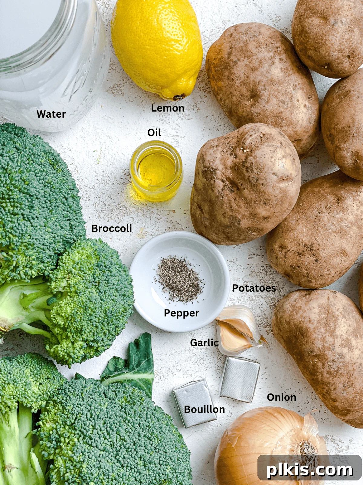 All the fresh and pantry ingredients for Vegan Broccoli Potato Soup laid out on a white surface.