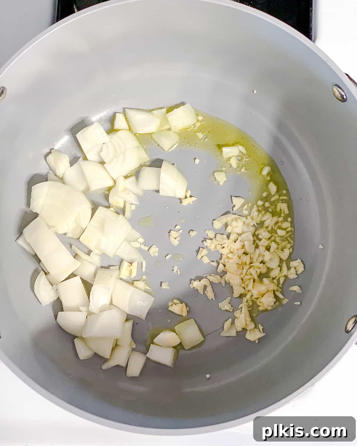 Process shot: Diced onions and minced garlic gently cooking in a pot.