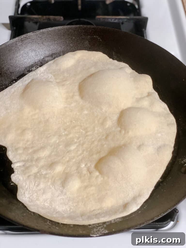 Handcrafted Flour Tortillas 14 Process shot showing a tortilla cooking on a pan, beginning to puff up with golden spots.