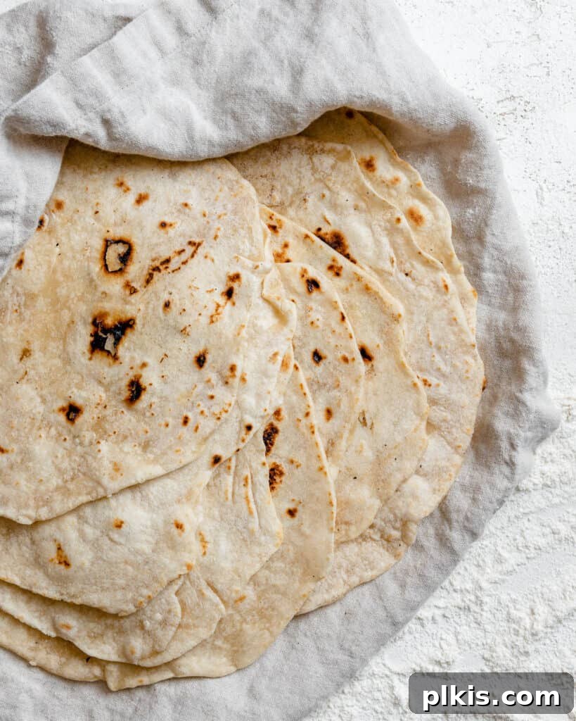 Handcrafted Flour Tortillas 15 Completed Tortillas de Harina – Handmade Flour Tortillas stacked on one another against a white surface, showing their inviting texture and warmth.