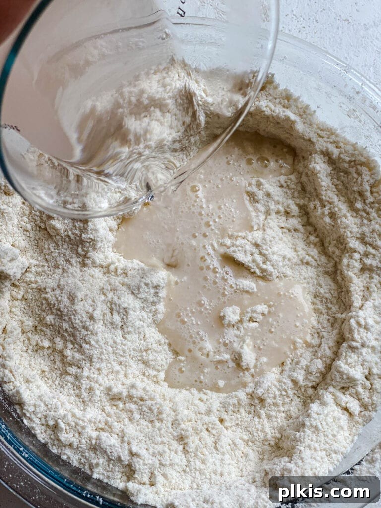 Handcrafted Flour Tortillas 7 Process shot of adding the liquid salt mixture to the dry ingredients in the mixing bowl.