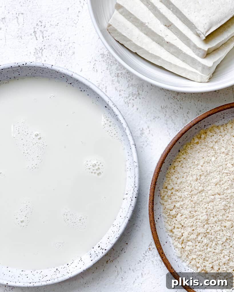 A visual representation of the wet and dry ingredients laid out alongside a plate of pressed tofu slices, demonstrating the setup for the breading process of the Easy Crispy Buffalo Tofu Sandwich.