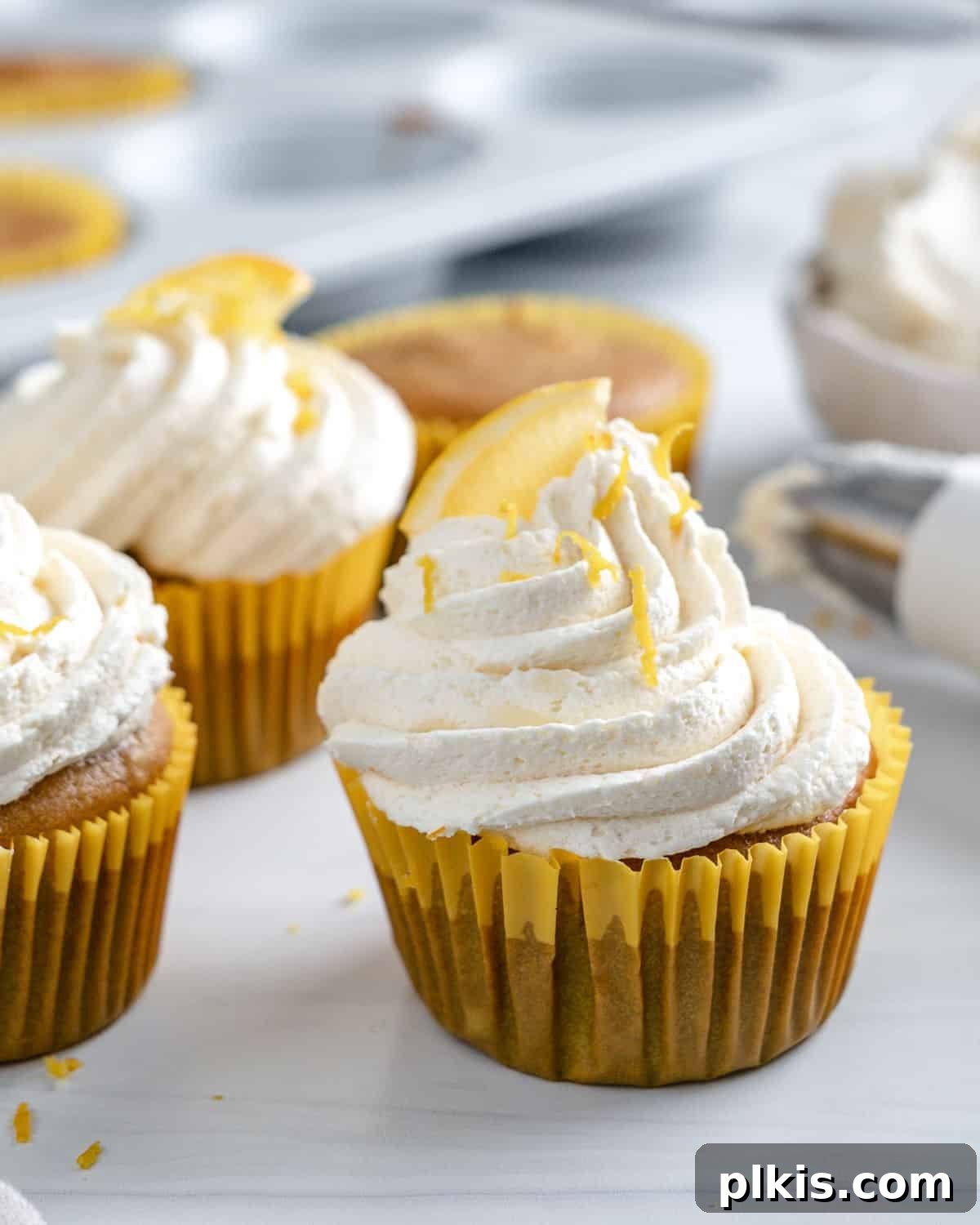 Effortless Vegan Lemon Cupcakes 6 A trio of beautifully frosted vegan lemon cupcakes arranged artistically on a white background.