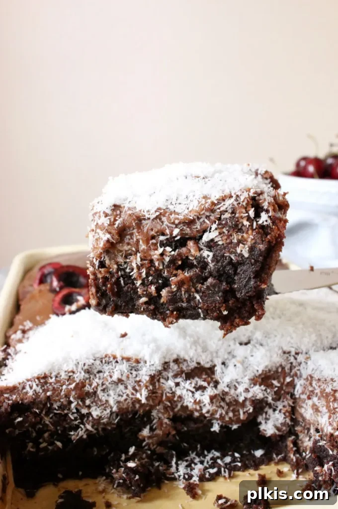 35 Irresistible Vegan Cake Creations 7 A tantalizing slice of vegan chocolate sheet cake, lifted from the pan to reveal its moist layers and rich frosting, set against a soft, light background.