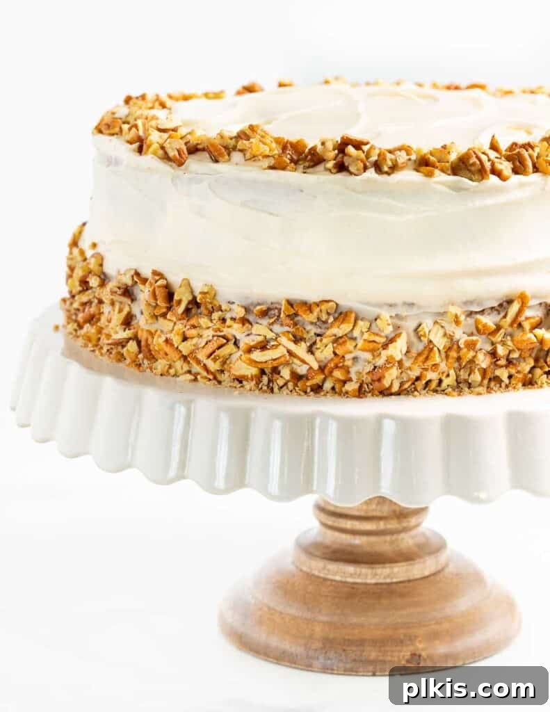 35 Irresistible Vegan Cake Creations 12 A magnificent vegan Hummingbird Cake, lavishly frosted and presented on an elegant cake platter, standing against a clean white background.