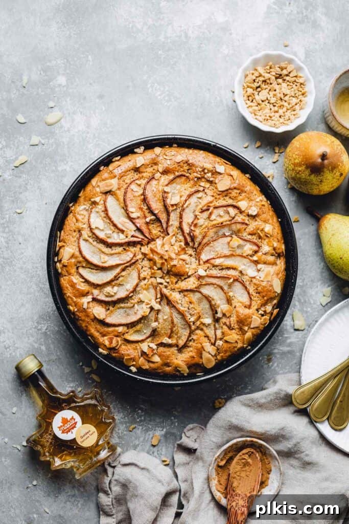 35 Irresistible Vegan Cake Creations 16 A delectable vegan pear cake, perfectly sliced and served on a sleek black plate, set against a complementary gray background.