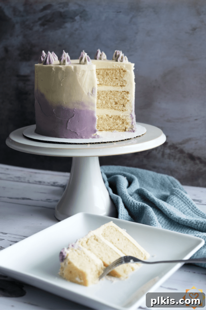 35 Irresistible Vegan Cake Creations 3 A pristine vegan vanilla cake displayed on an elegant cake platter, with a smaller plate holding a slice of cake in the foreground, ready to be enjoyed.
