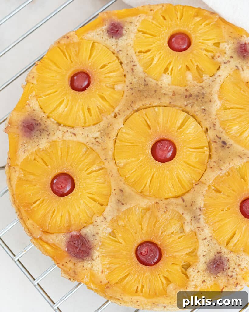 35 Irresistible Vegan Cake Creations 20 A vibrant and delicious vegan pineapple upside-down cake, glistening and inviting, showcased against a clean white surface.