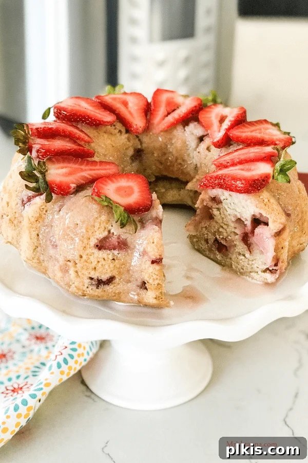 35 Irresistible Vegan Cake Creations 28 A gorgeous Instant Pot strawberry Bundt cake on a cake platter, with a slice already removed, showcasing its moist interior.