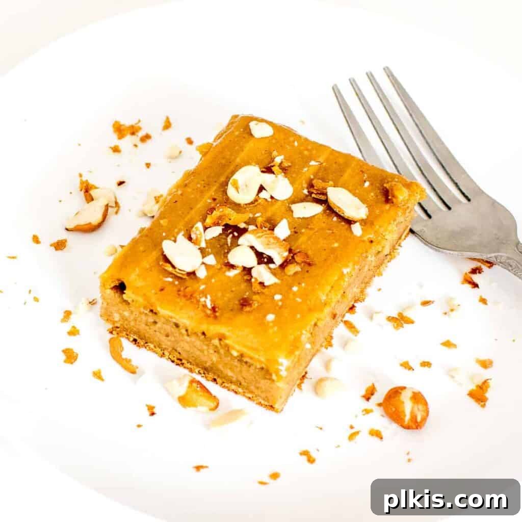 35 Irresistible Vegan Cake Creations 40 A delectable slice of vegan peanut butter cake, adorned with frosting and served on a white plate with a fork beside it.