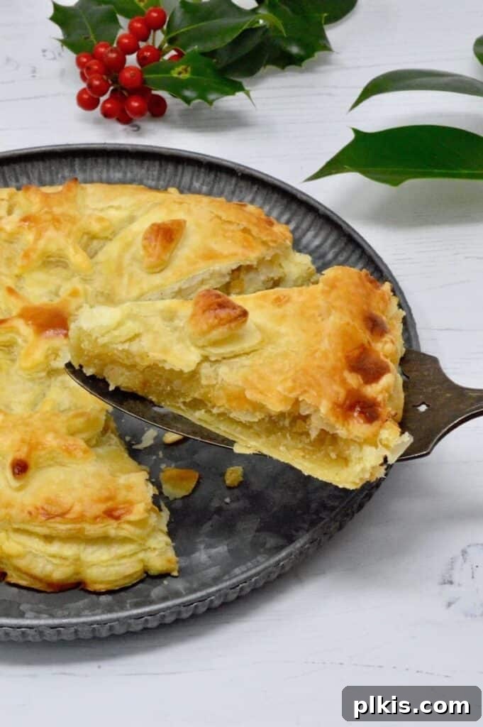 35 Irresistible Vegan Cake Creations 42 A stunning vegan King Cake (Galette des Rois), with a piece elegantly lifted to showcase its flaky pastry and rich filling, against a clean white background.